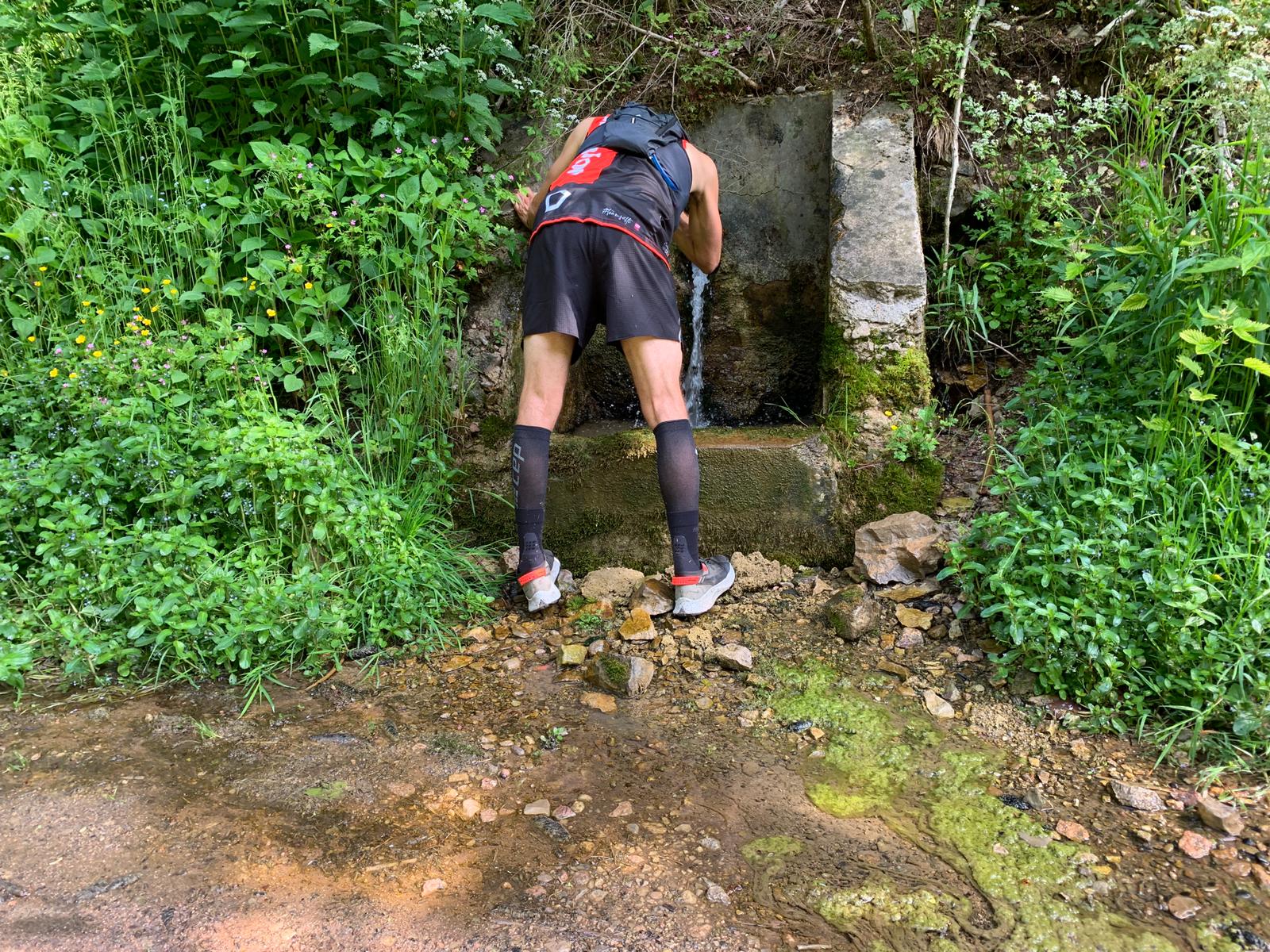 Erik füllt an einer Quelle auf dem Wasserweltensteig Wasser nach